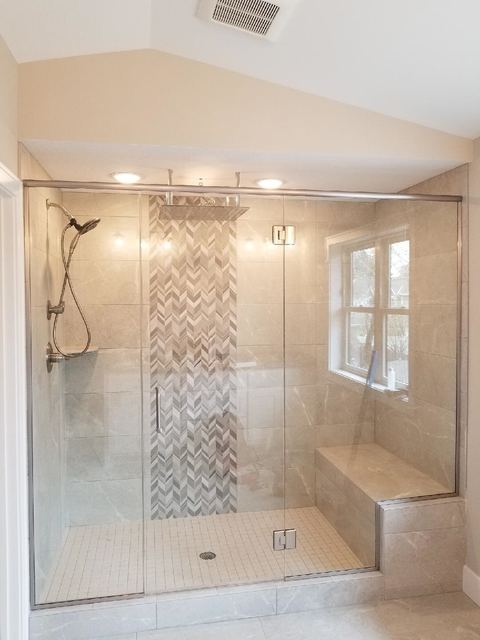Frameless corner shower with a bench and herringbone tile accent