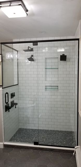 Frameless shower with black hinges and white subway tile