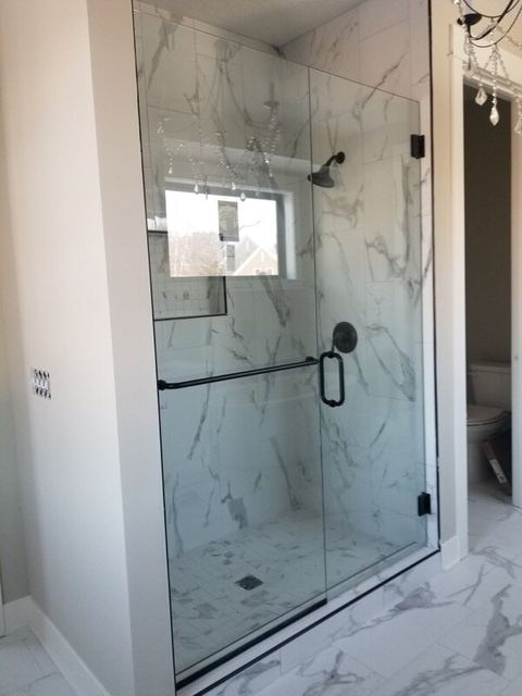 Frameless shower with a matte black towel bar handle