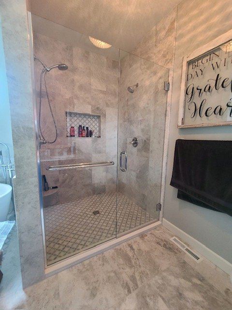 Frameless enclosure with gray tile and a mosaic floor