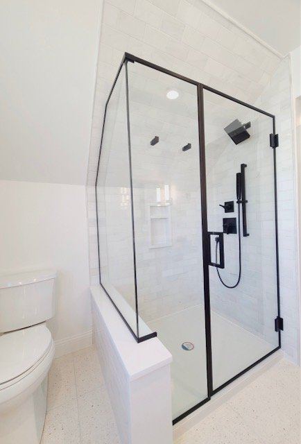 Frameless shower with black hardware on a knee wall