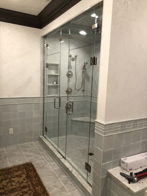 Frameless enclosure on a knee wall with gray tile