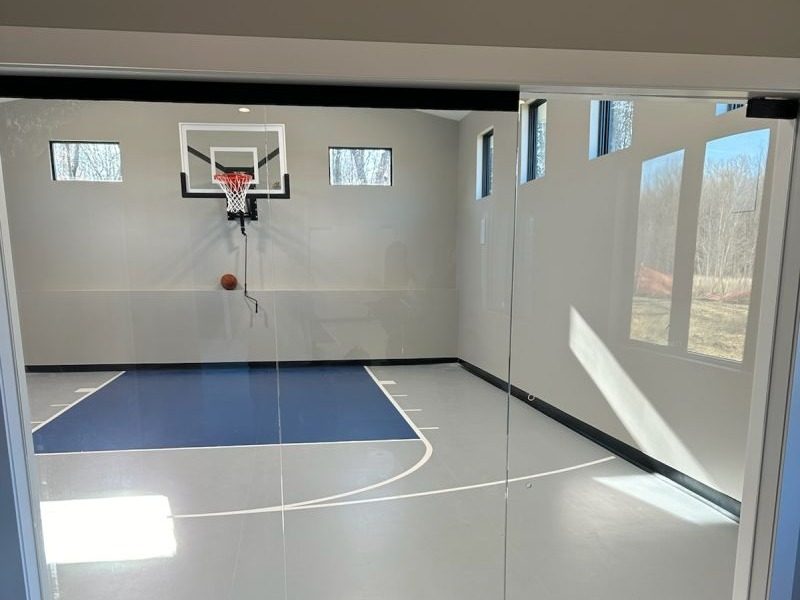 Frameless glass wall and door into a home sport court