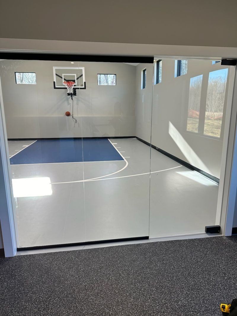 Frameless glass wall and door into a home sport court